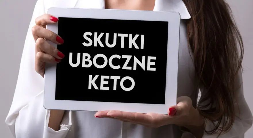 Kobieta trzyma tablet z napisem "SKUTKI UBOCZNE KETO". Warto wiedzieć, jakie są objawy problemów z jelitami przy tej diecie.