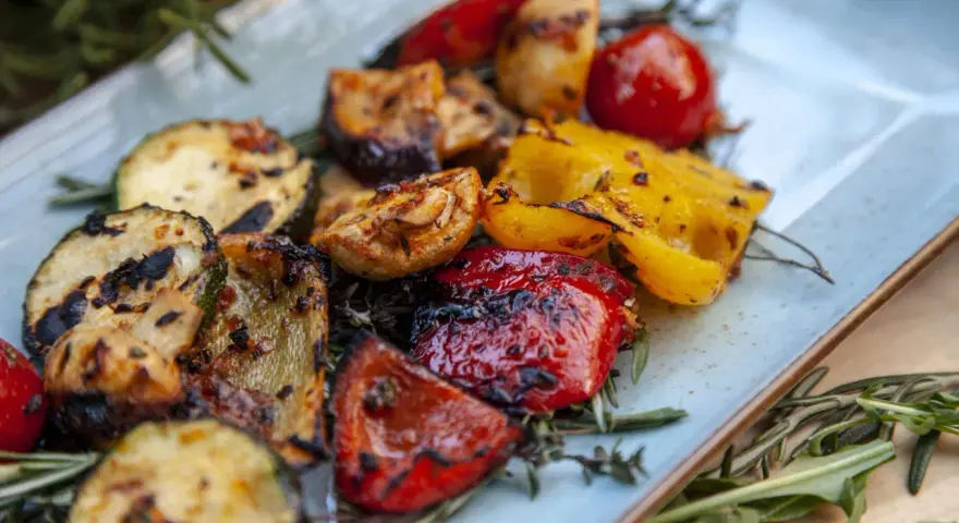 Gegrilltes Gemüse wie Zucchini, Paprika und Tomaten, garniert mit Rosmarin. Perfekt für Ihre nächsten BBQ Rezepte!