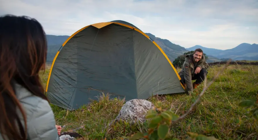 Mann und Frau biwakieren in Deutschland. Sie bauen ein Zelt in den Bergen auf, die Landschaft ist wunderschön.