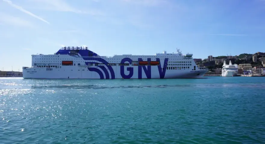Ogromny prom GNV Orion czeka na pasażerów, by zabrać ich w podróż na Sycylię. W tle widać port i wzgórza.
