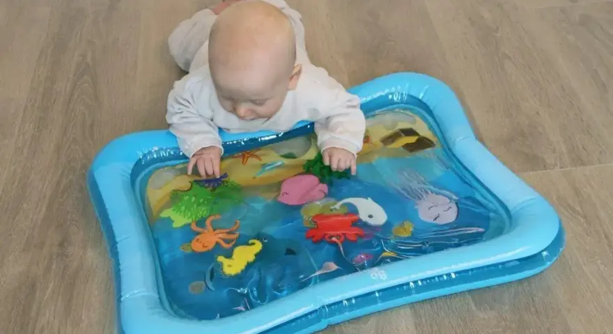 Niemowlę bawi się na macie wodnej dla niemowląt z morskimi stworzeniami.