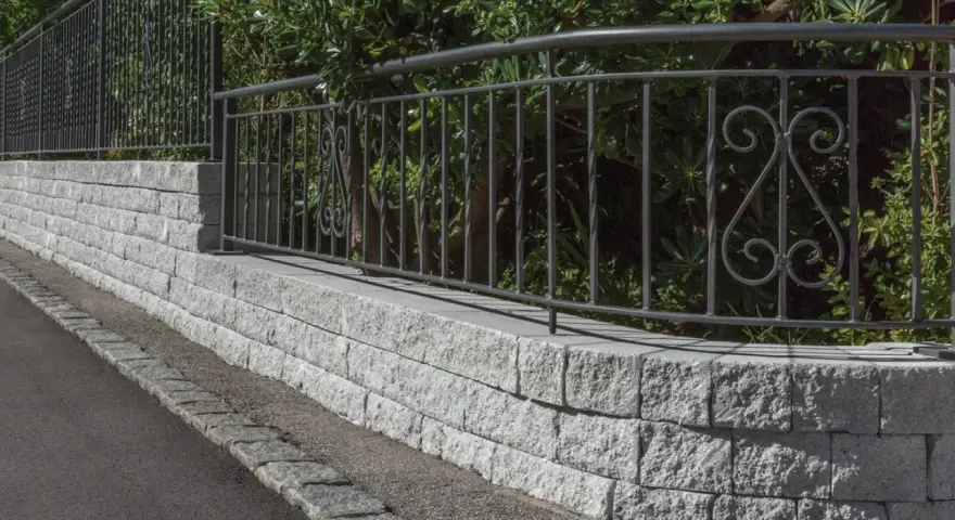 Muro in pietra grigia con ringhiera in ferro battuto, un'ottima idea per muri di recinzione moderni ed eleganti.