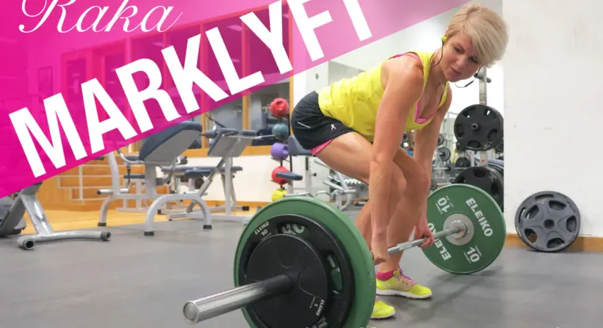 En kvinna utför raka marklyft med en skivstång i ett gym.