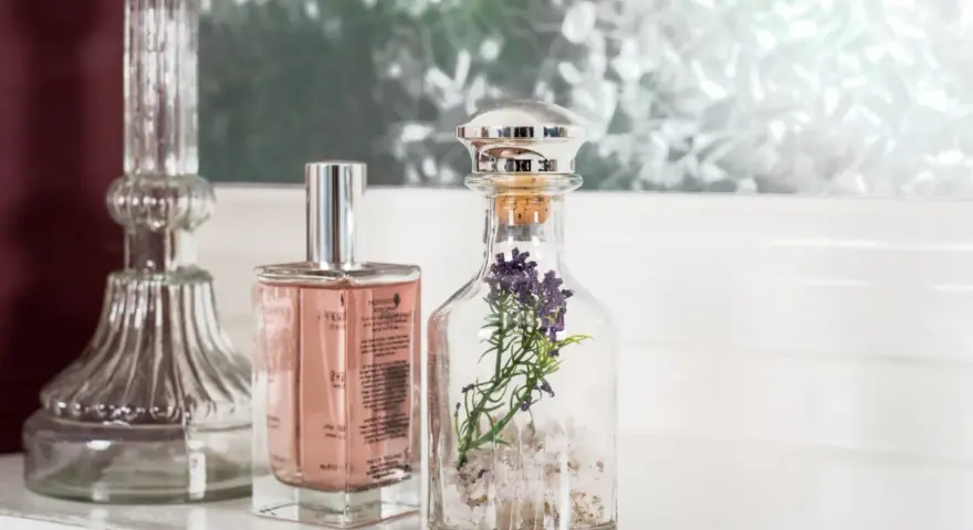 Eleganckie perfumetki męskie w szklanych buteleczkach, jedna z lawendą, obok ozdobnego świecznika.