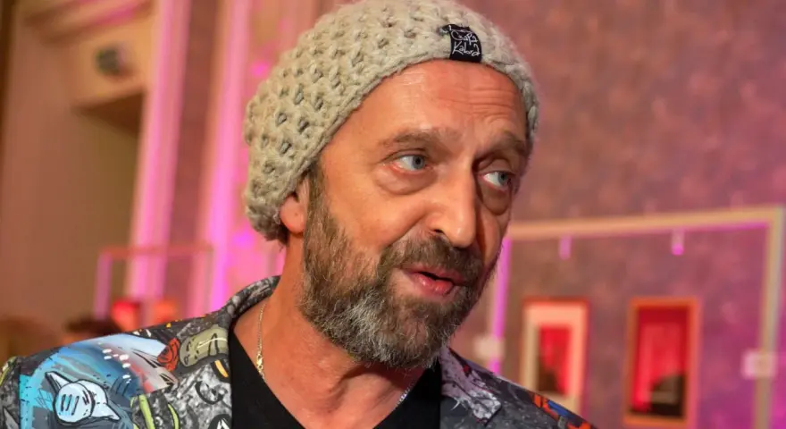 Nikodem Chabior w beżowej czapce i kolorowej kurtce, z zarostem, patrzy w bok.