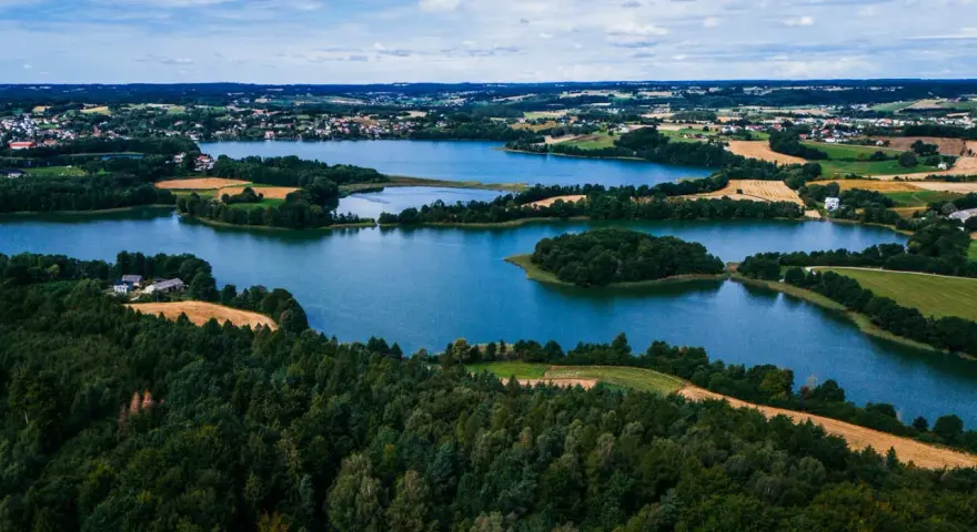 Malownicze jeziora i lasy tworzą tajemnicze miejsca na Kaszubach. Widok z lotu ptaka ukazuje spokojne wody, zielone wyspy i pola uprawne.