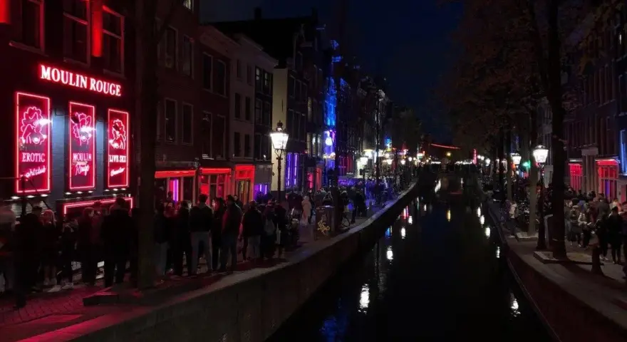 Nocna czerwona ulica Amsterdamu z kanałem i neonami.