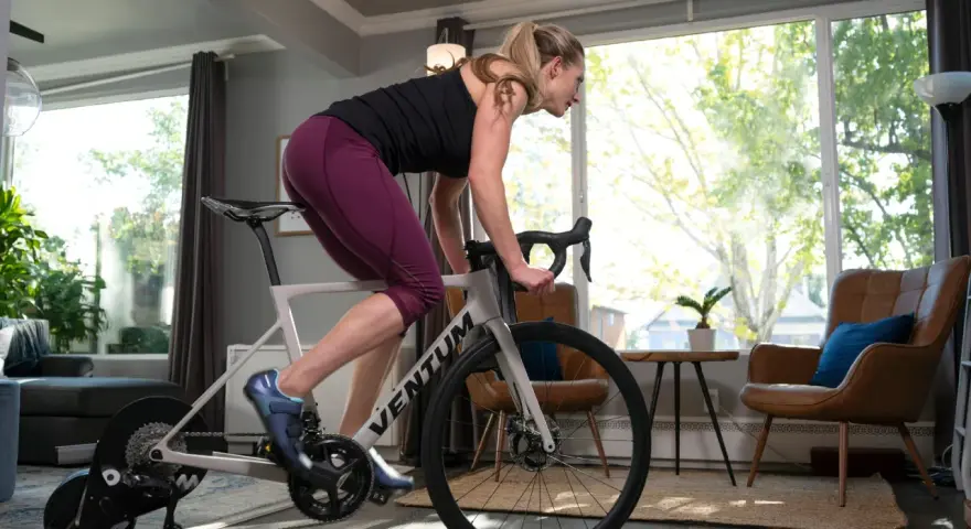 Woman training on a bike trainer in a living room. This indoor bike setup allows for a great workout at home.