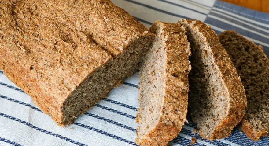 Ein frisch gebackenes vollkornbrot mit hefe, aufgeschnitten auf einem gestreiften Tuch.