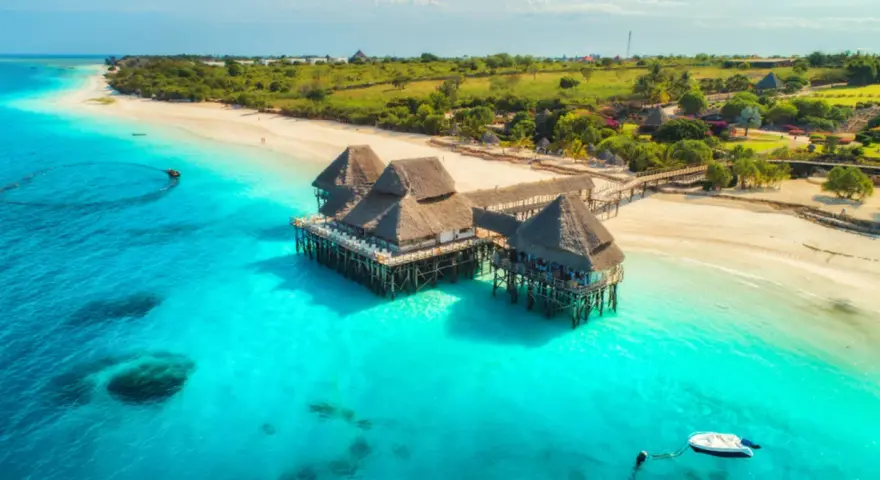 Rajskie plaże i turkusowa woda, idealne tanzania atrakcje. Domki na palach w tropikalnym otoczeniu.