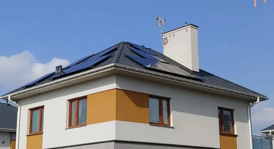 Nowy dom z panelami fotowoltaicznymi na dachu, korzystający z systemu net metering.