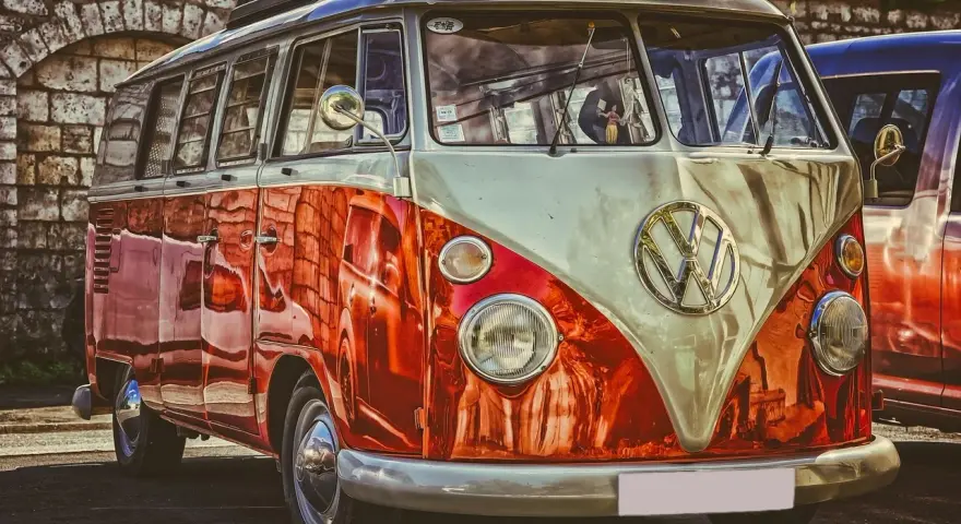 Klasyczny VW Transporter, idealny do transportu gości weselnych. Jego jaskrawy, dwukolorowy lakier przyciąga wzrok.