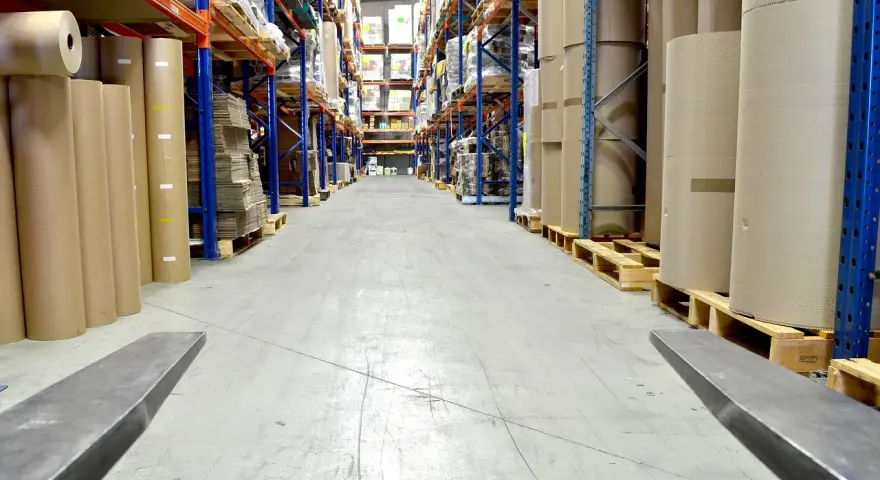 Magazyn z rolkami papieru i kartonami. Wózek widłowy gotowy do pracy, być może z systemem kod rfid do śledzenia towaru.
