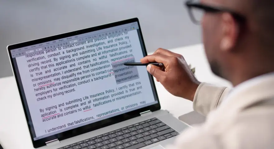 Un homme examine un document sur un écran d'ordinateur, soulignant des passages pour apprendre comment reconnaître une pièce fautée.