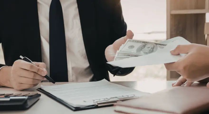 Biznesmen przekazuje kopertę z pieniędzmi, podczas gdy drugi mężczyzna podpisuje dokument. Szybka gotówka windykacja terenowa.