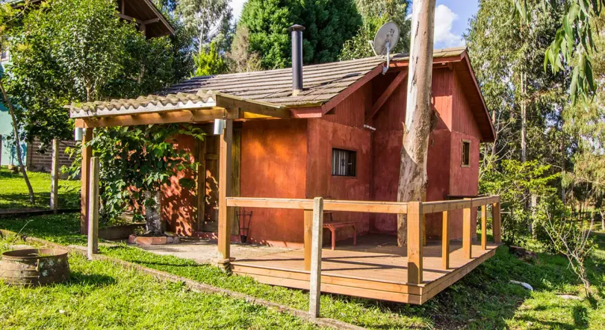 Il progetto di una piccola casa di campagna, con tetto spiovente, camino e un albero che attraversa la struttura.