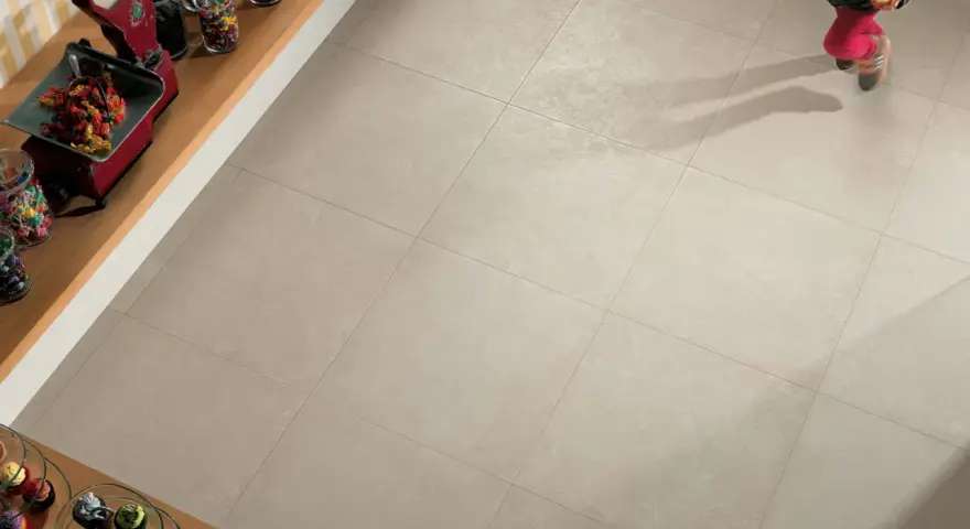 Un enfant court sur un sol carrelé 60x60. L'épaisseur du joint du carrelage est subtile, soulignant la modernité de la pose.