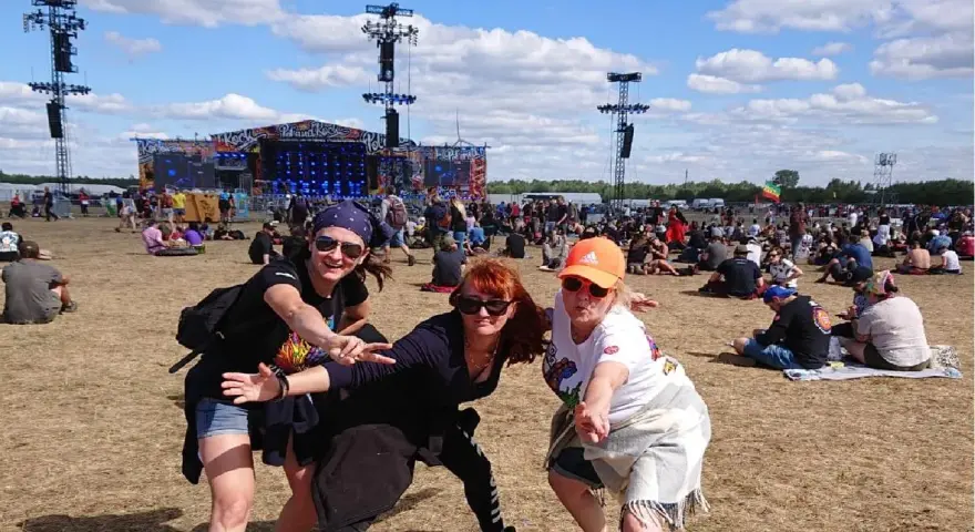 Trzy kobiety bawią się na festiwalu czaplinek pol and rock. W tle scena i tłum ludzi.