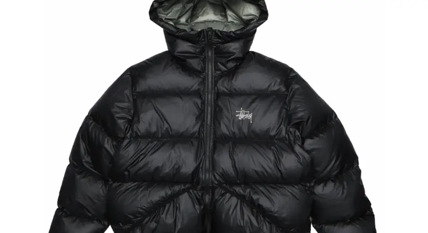 Piumino nero Stussy con cappuccio e logo bianco sul petto. Perfetto per affrontare il freddo con stile.