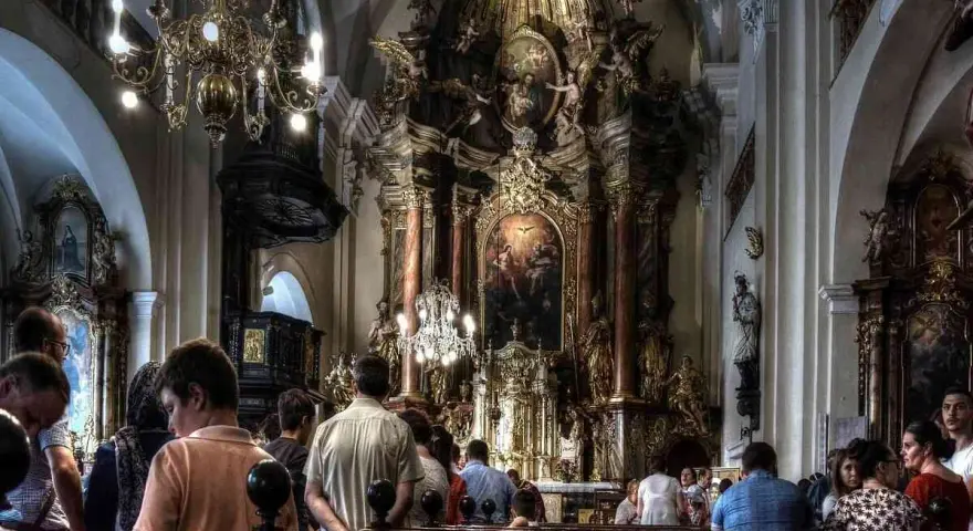 Wnętrze kościoła z bogato zdobionym ołtarzem. Ludzie siedzą w ławkach, słuchając kazania. Czy to czas na gorzkie żale?