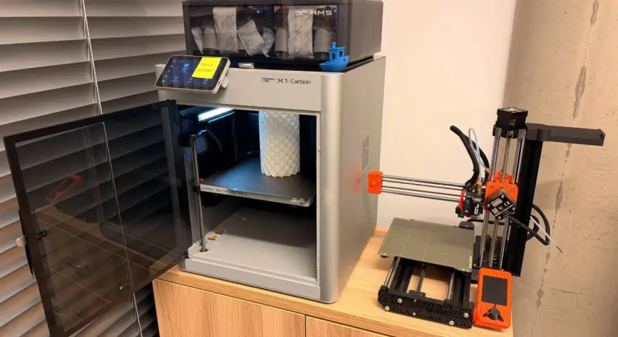 Test drukarki 3D Bambu Lab X1-Carbon z AMS i małą drukarką Prusa Mini obok.
