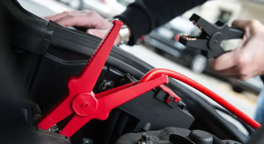 Rotes Kabel mit Krokodilklemme wird an Autobatterie angeschlossen. Plus oder Minus?