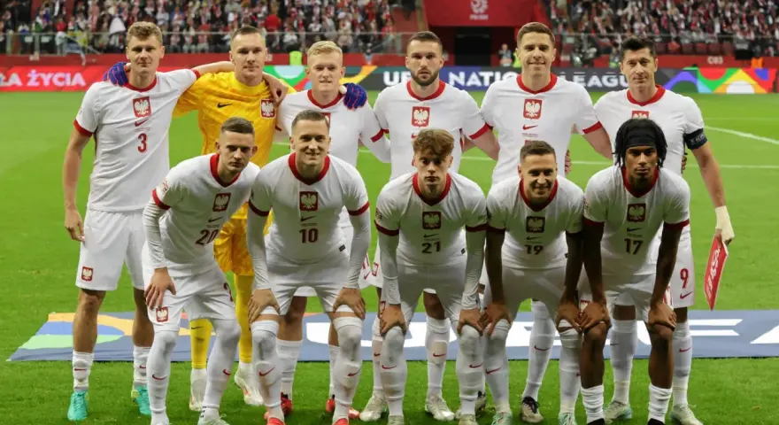 Piłkarze reprezentacji Polski w białych strojach, gotowi do gry. Wszyscy z orzełkiem na piersi, czekają na dobry wynik Polska.