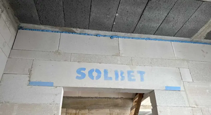 Dylatacja co to? Widoczna szczelina wypełniona pianką między betonem a bloczkami z napisem SOLBET.