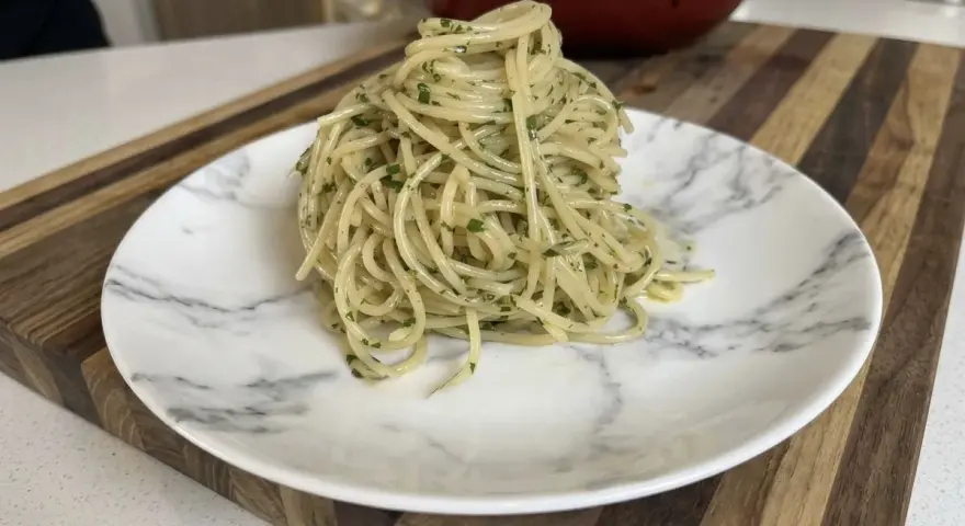 Un plato de spaghetti aglio e olio, con perejil picado, listo para disfrutar.