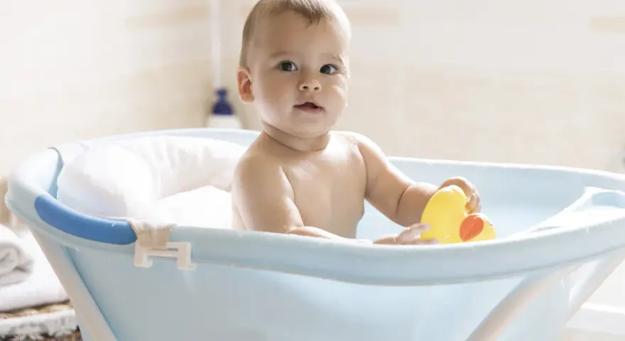 Urocze dziecko w niebieskiej wanience z żółtą kaczką. Kąpiel w wanience jest świetną zabawą, a dziecko może w niej przebywać, dopóki nie zacznie samodzielnie siadać i wstawać.