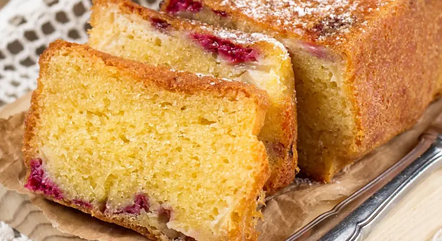 Puszyste ciasto z serka wiejskiego z malinami, posypane cukrem pudrem. Idealne na podwieczorek.