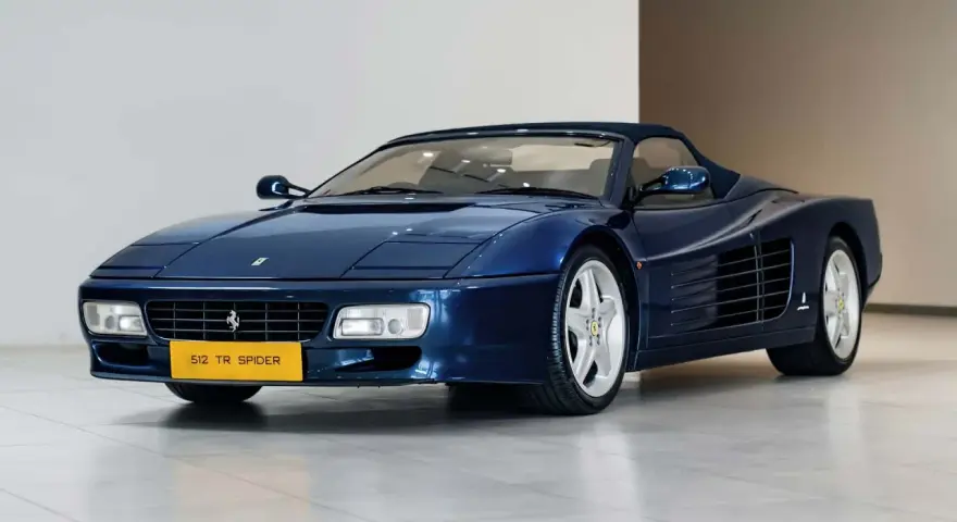 Niebieskie Ferrari 512 TR Spider z lat 90. błyszczy na wystawie, gotowe na przejażdżkę.