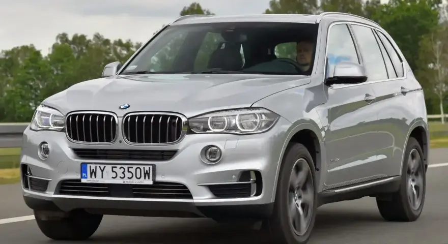 Srebrne BMW X5 E70 w ruchu. Kierowca za kierownicą. Rozpiska bezpieczników BMW X5 E70 jest kluczowa dla jego sprawnego działania.