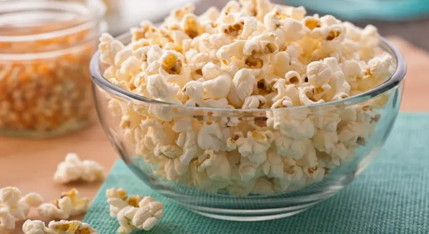 Misternie ułożony popcorn w szklanej misce. Czy popcorn jest zdrowy? To zależy od sposobu przygotowania, ale sam w sobie jest dobrym źródłem błonnika.
