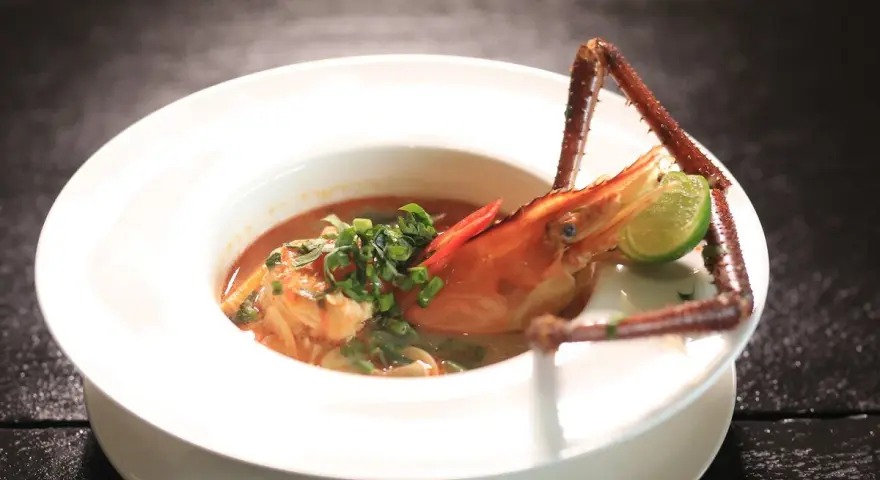 Sopa de marisco con gamba, lima y chile en plato blanco.