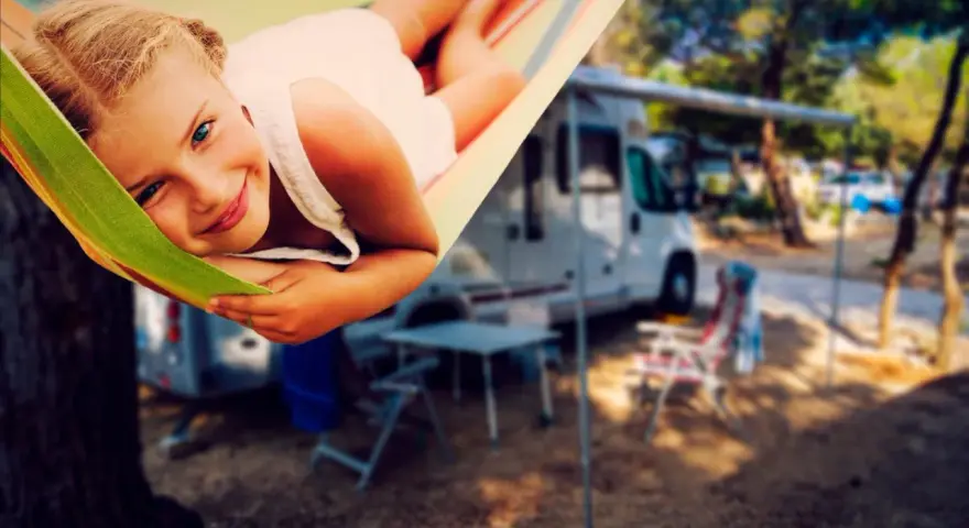 Ein glückliches Mädchen entspannt sich in einer Hängematte auf einem familienfreundlichen Campingplatz. Im Hintergrund stehen Wohnmobile und Campingmöbel.