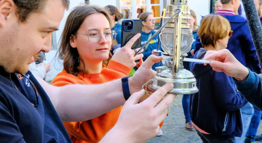 Eine Frau hält ein Handy, während eine Kerze das altenberger licht entzündet.