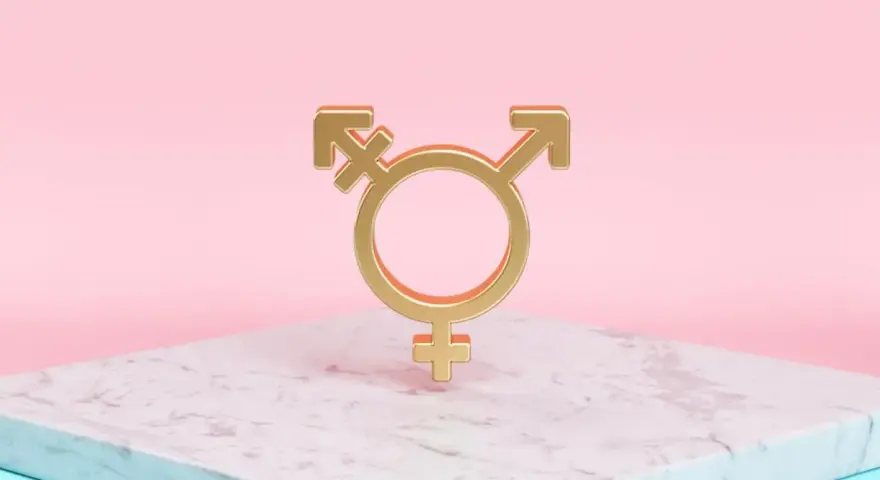 Złoty symbol trans, łączący symbole Wenus, Marsa i hermafrodyty, na marmurowej podstawie.