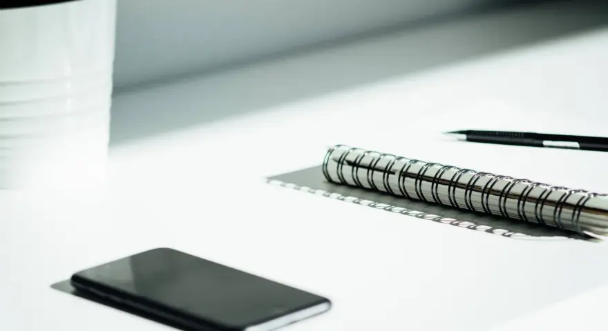 A smartphone, notebook, and pen sit on a desk, ready for a startup auditor's analysis.