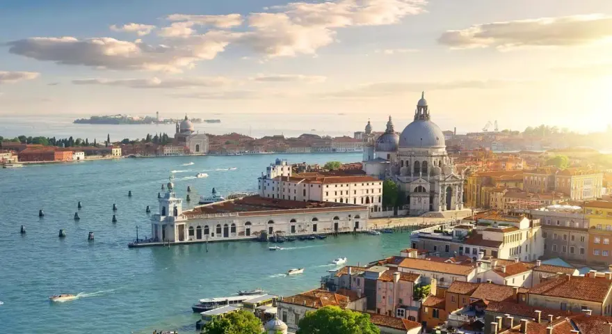Venice cityscape with canals, boats, and historic buildings under a sunny sky.