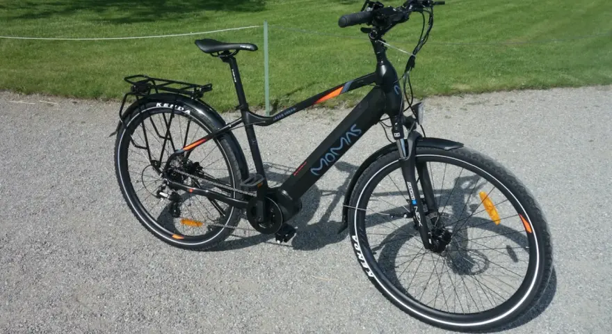 Svart elcykel, modell MOMAS JASON URBAN, redo för ett momas elcykel test. Ställning bak, skärmar och reflexer syns tydligt.
