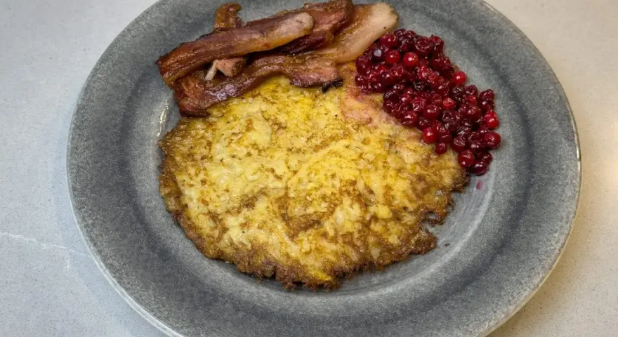 En tallrik med raggmunk, stekt fläsk och lingon. Ett klassiskt svenskt raggmunk recept som är perfekt för en mysig middag.