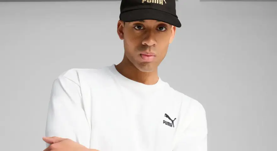 Mężczyzna w czarnej czapce z logo Puma i białej koszulce.