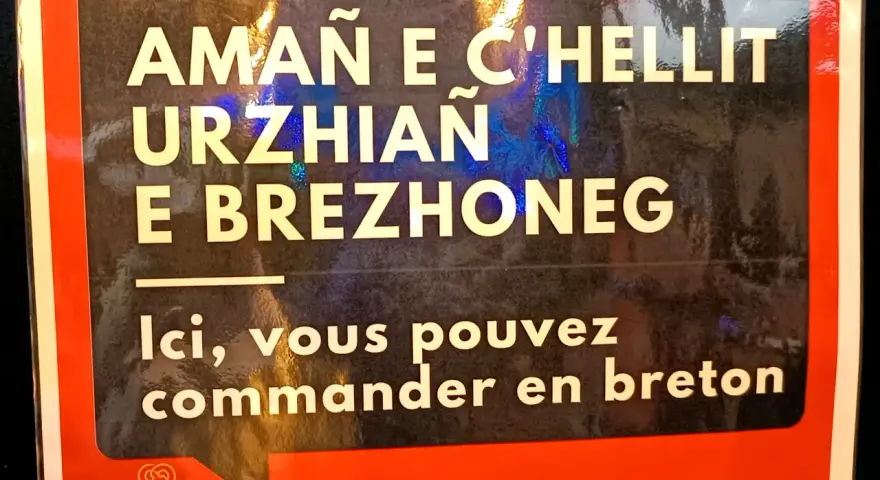 Cartel en bretón y francés: "Aquí puedes pedir en bretón". Un festival en Bretaña, Francia.