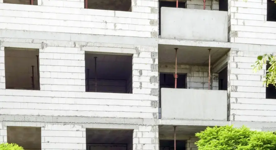 Budowa bloku mieszkalnego, widoczne puste okna i balkony. W przyszłości powstanie tu mieszkanie komunalne.