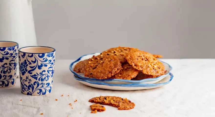 Deliciosas galletas de jengibre con trocitos de nuez, servidas en un plato azul y blanco.