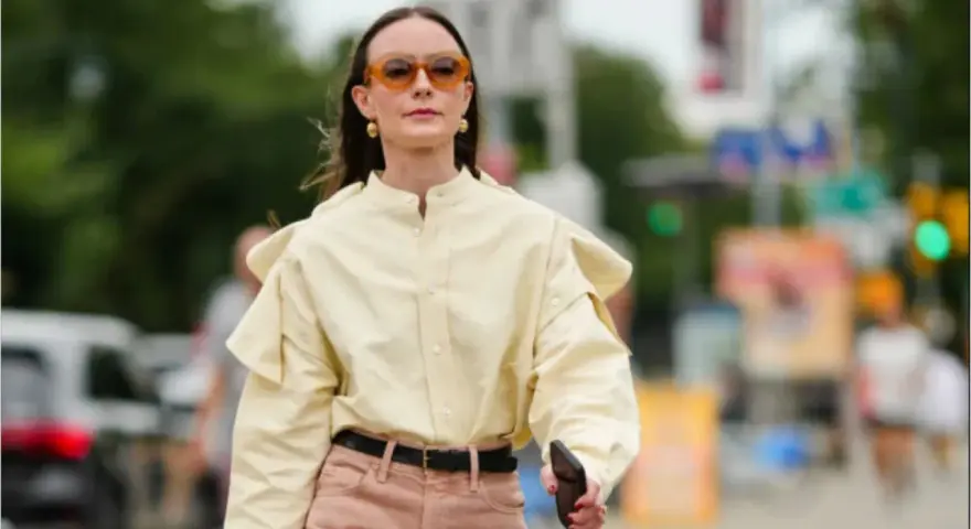 Donna con camicia gialla e pantaloni rosa. Un esempio di pantaloni rosa abbinamenti perfetti per un look casual chic.