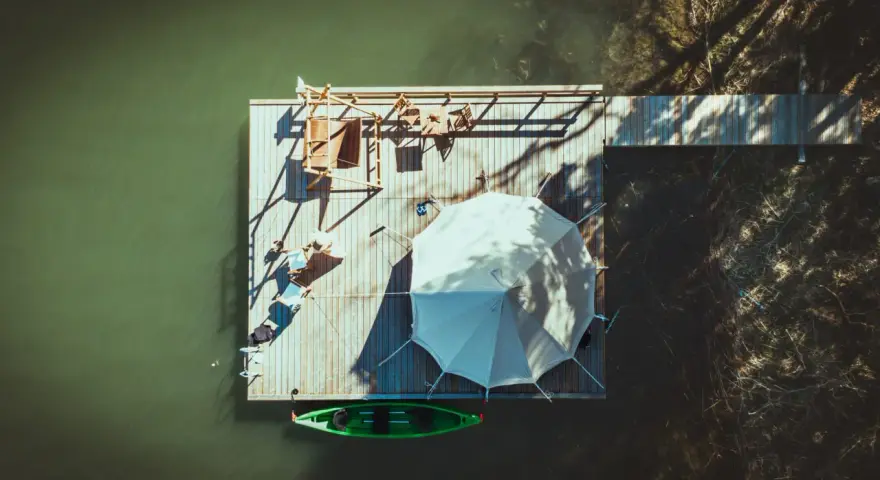 En flytande plattform vid Marholmen camping med tält, solstolar och en grön kajak.