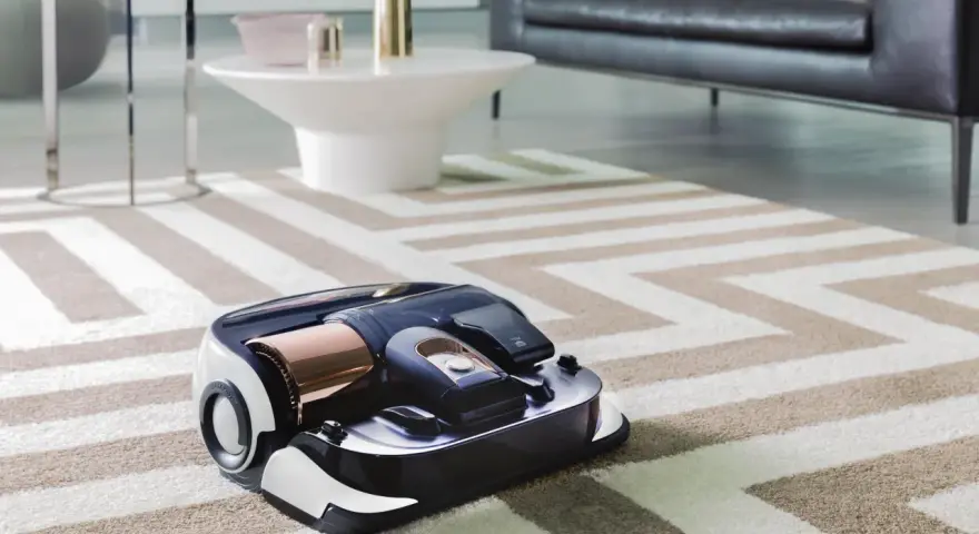 En modern robotdammsugare arbetar på en randig matta i ett stilrent vardagsrum.