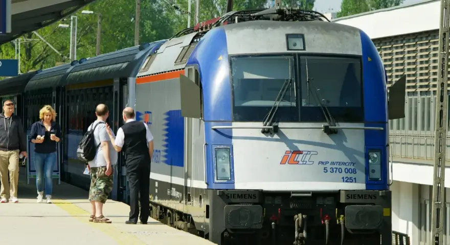 Pasażerowie czekają na pociąg PKP Intercity, gotowi do podróży z biletem wakacyjnym.